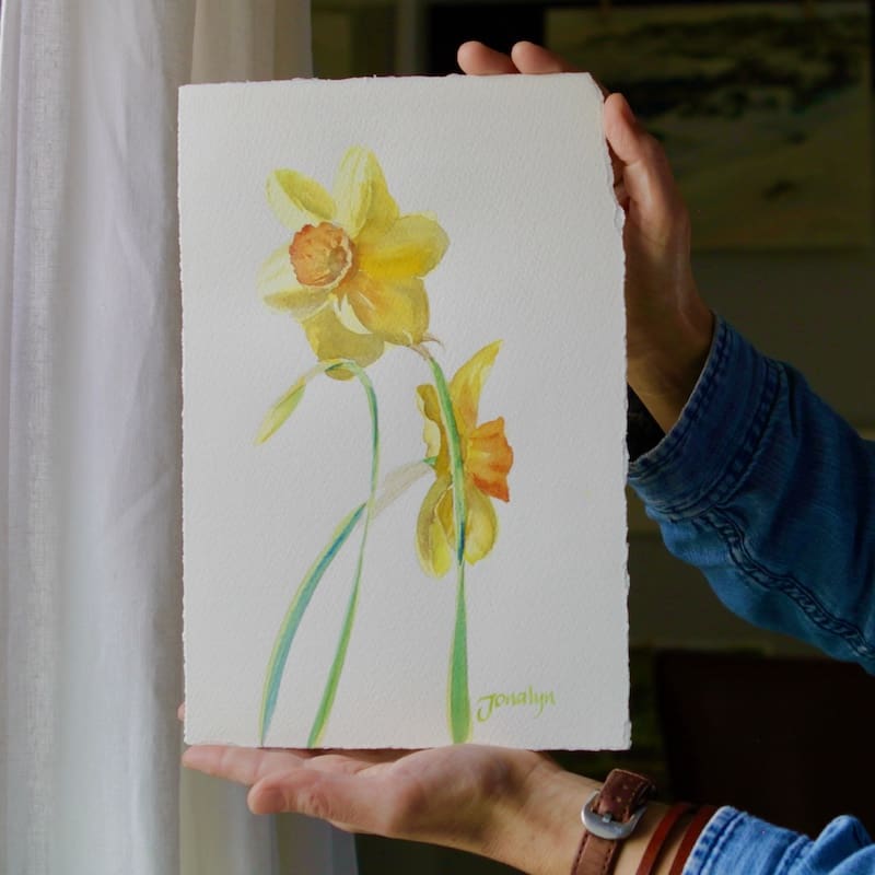 A watercolor painting of three yellow daffodils. 