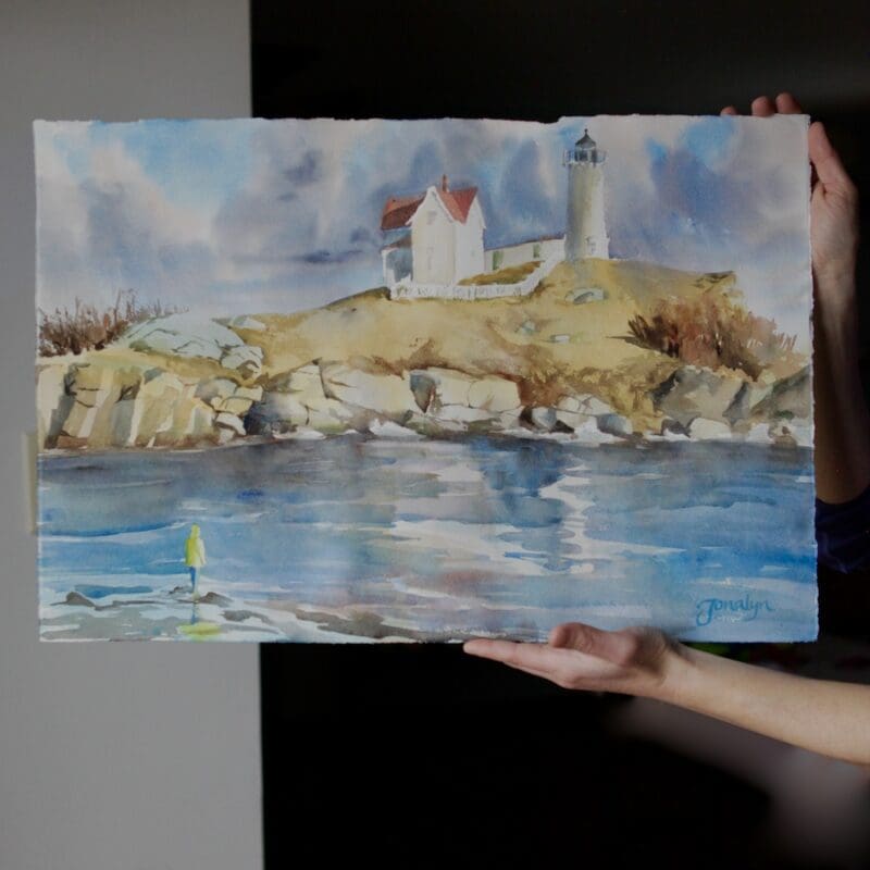 Nubble Lighthouse Reflections watercolor painting with white lighthouse, blue water reflecting sky.